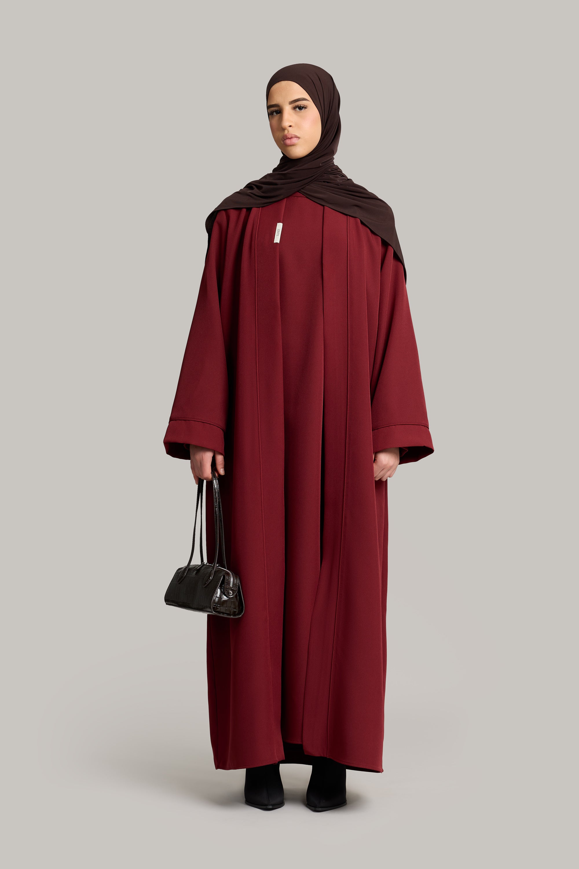 model draagt essential abaya set in de kleur burgundy van het merk enti