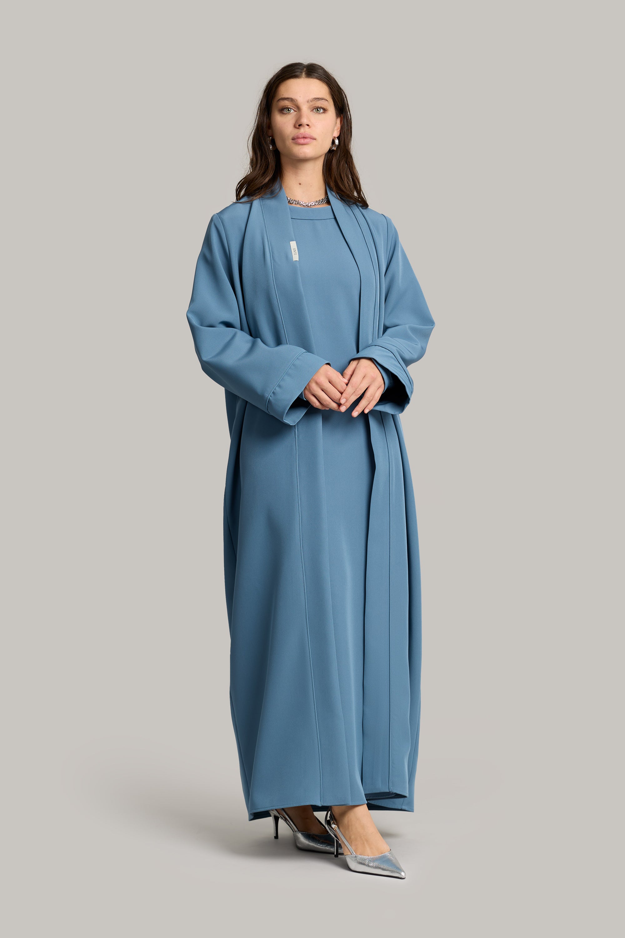 model draagt de essential abaya en kimono set in de kleur zacht blauw van het merk ENTI met haar handen tegen elkaar.