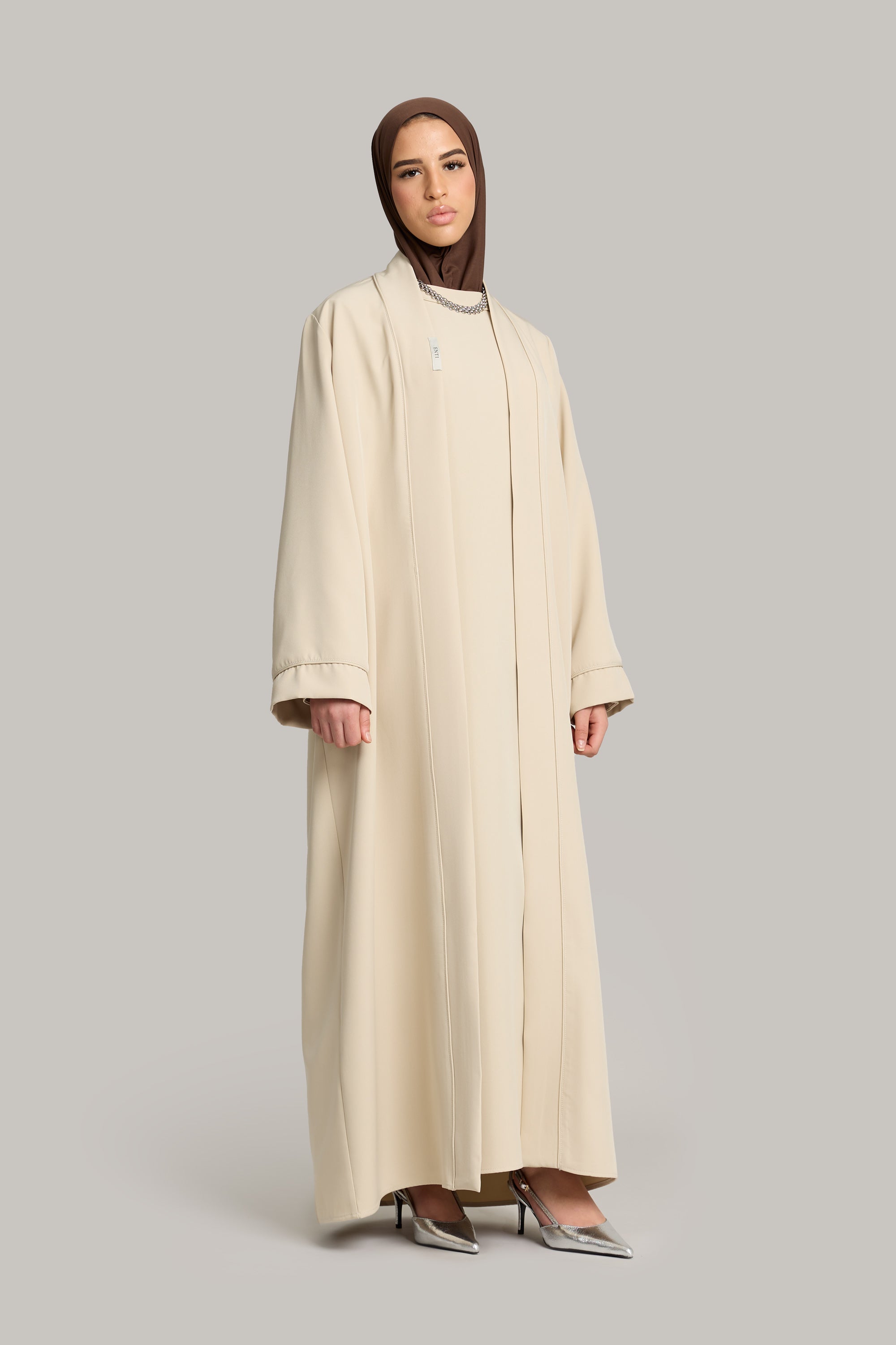 model draagt de essential abaya en kimono set in de kleur sand van het merk ENTI.